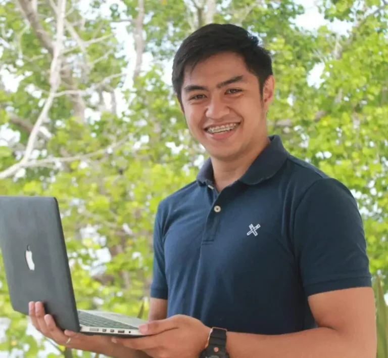 Rogel Alonzo, Senior Web Developer at Bloom Digital Marketing, holding a laptop outdoors